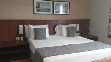 A hotel room with a large bed, two bedside tables, and two framed pictures on the wall.