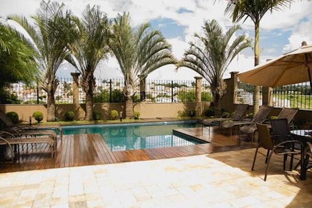 Una piscina al aire libre, sillones reclinables de piscina