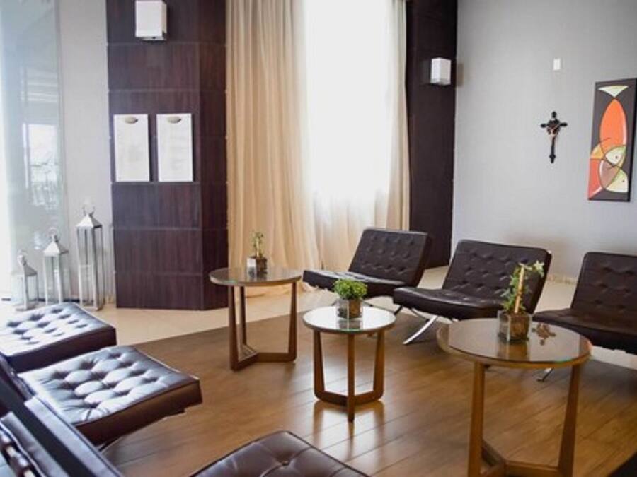 A modern living room with a sofa set, two round tables, and a large window with curtains.