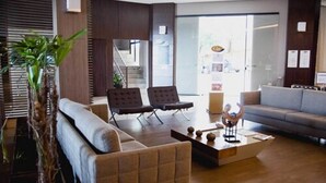 A modern hotel lobby with a sofa, two armchairs, a coffee table, and a plant. - Class Hotel Varginha (Varginha)