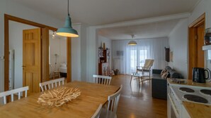 A spacious kitchen with a wooden table and chairs, a stove, and a dining area with a chair. - Gamla húsið - The old house (Sveitarfélagid Ölfus)