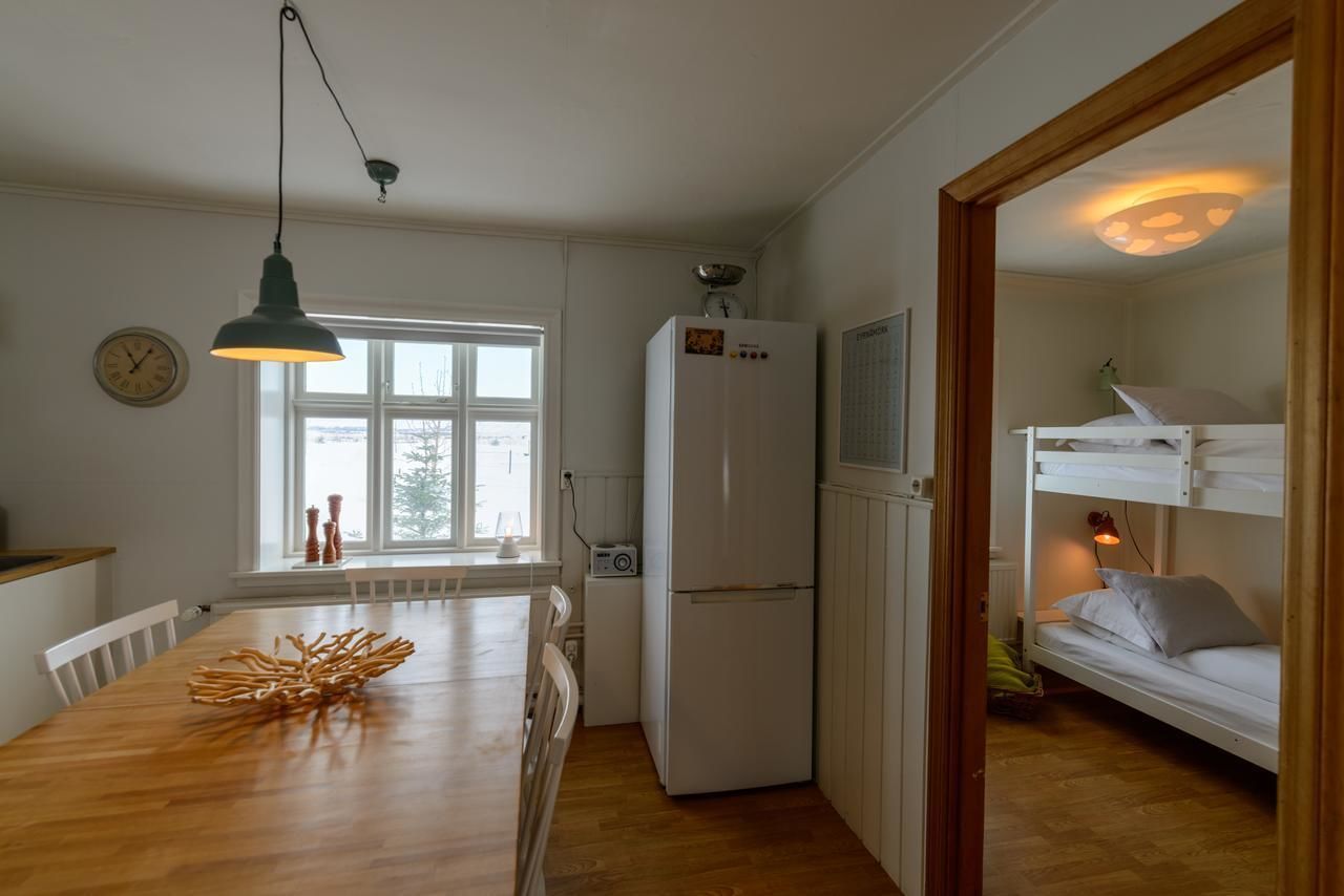 A compact kitchen with a wooden table, a white refrigerator, and a window.