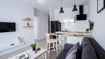 Relax in this stylish living space with a flat-screen TV, dining table, and comfortable sofa.