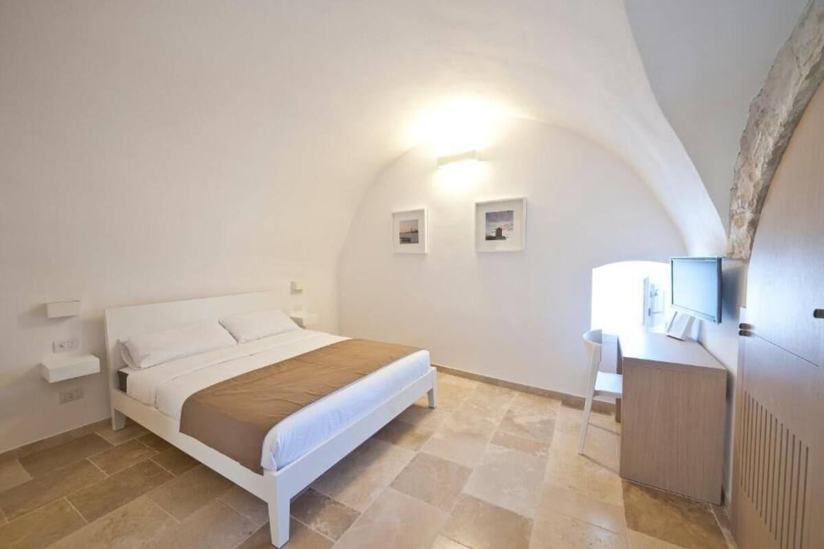 Un dormitorio con cama, escritorio y televisor.
