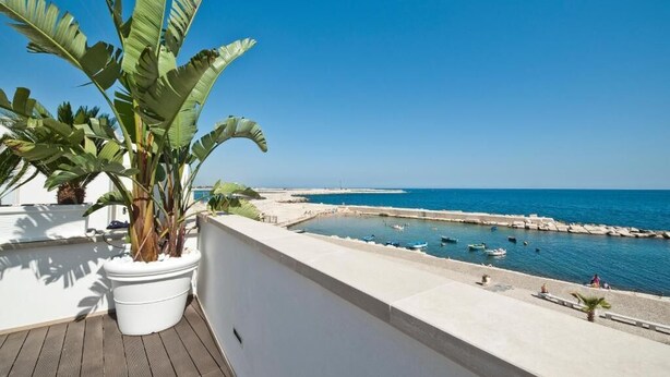 A balcony with a potted plant, a view of the sea, and boats in the water. - MoMa Molfetta Mare (Molfetta)