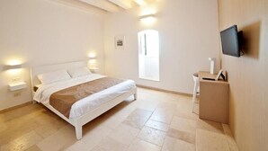 A bedroom with a bed, bedside tables, a TV, and a window. - MoMa Molfetta Mare (Molfetta)