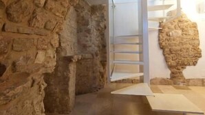 A stone-walled interior with a staircase leading to an upper level. - MoMa Molfetta Mare (Molfetta)