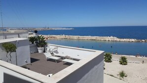A rooftop terrace with a view of the sea, lounge chairs, and potted plants. - MoMa Molfetta Mare (Molfetta)