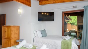 A hotel room with two beds, a television, a wooden cabinet, and a sliding glass door leading to an outdoor area. - San Lameer Villa Rentals  2843 (Southbroom)