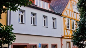 A traditional European building with a cobblestone street, a wooden door, and a blue parking sign. - Konventchen (Aschaffenburg)