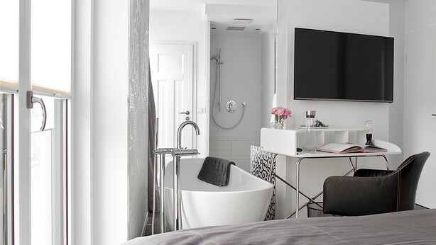 A modern bathroom with a bathtub, shower, and a vanity with a mirror and sink. - Konventchen (Aschaffenburg)