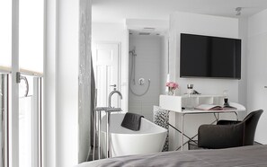 Une salle de bain moderne équipée d’une baignoire, d’une douche et d’un meuble-lavabo avec un miroir et un évier.