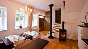 A cozy dining area with a wooden table set for two, a chandelier, and a stone wall. - Konventchen (Aschaffenburg)