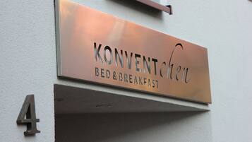 A metal sign with the text "KONVENTICHEN BED & BREAKFAST" mounted on a wall, indicating a bed and breakfast establishment.