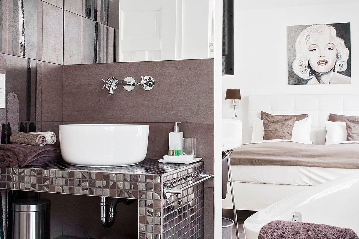 A modern bathroom with a large white sink, a mirror, and a towel rack.