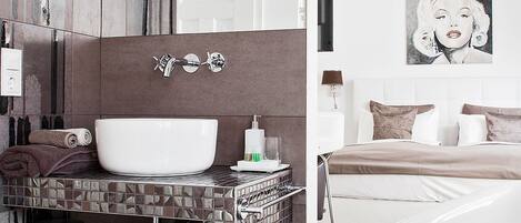 A modern bathroom with a large white sink, a mirror, and a towel rack.