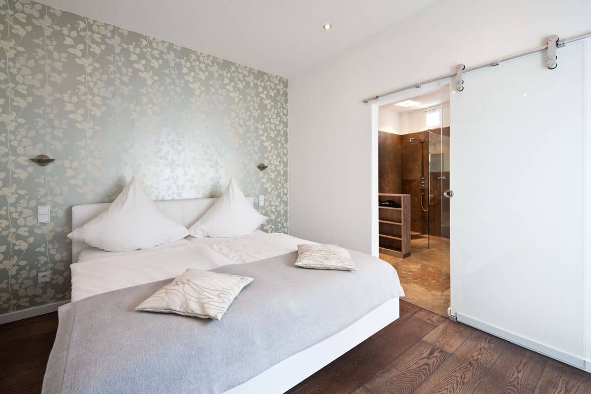 A bedroom with a bed, a wardrobe, and a bathroom with a shower.