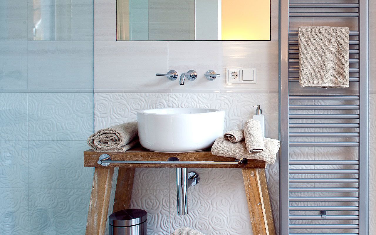 A bathroom with a white sink, wooden vanity, towel rack, and a towel on the wall.