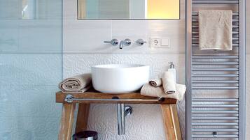 A bathroom with a white sink, wooden vanity, towel rack, and a towel on the wall.