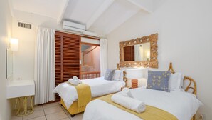 A hotel room with two beds, a bedside table, a mirror, and a window with wooden shutters. - San Lameer Villa Rentals 3501 (Southbroom)