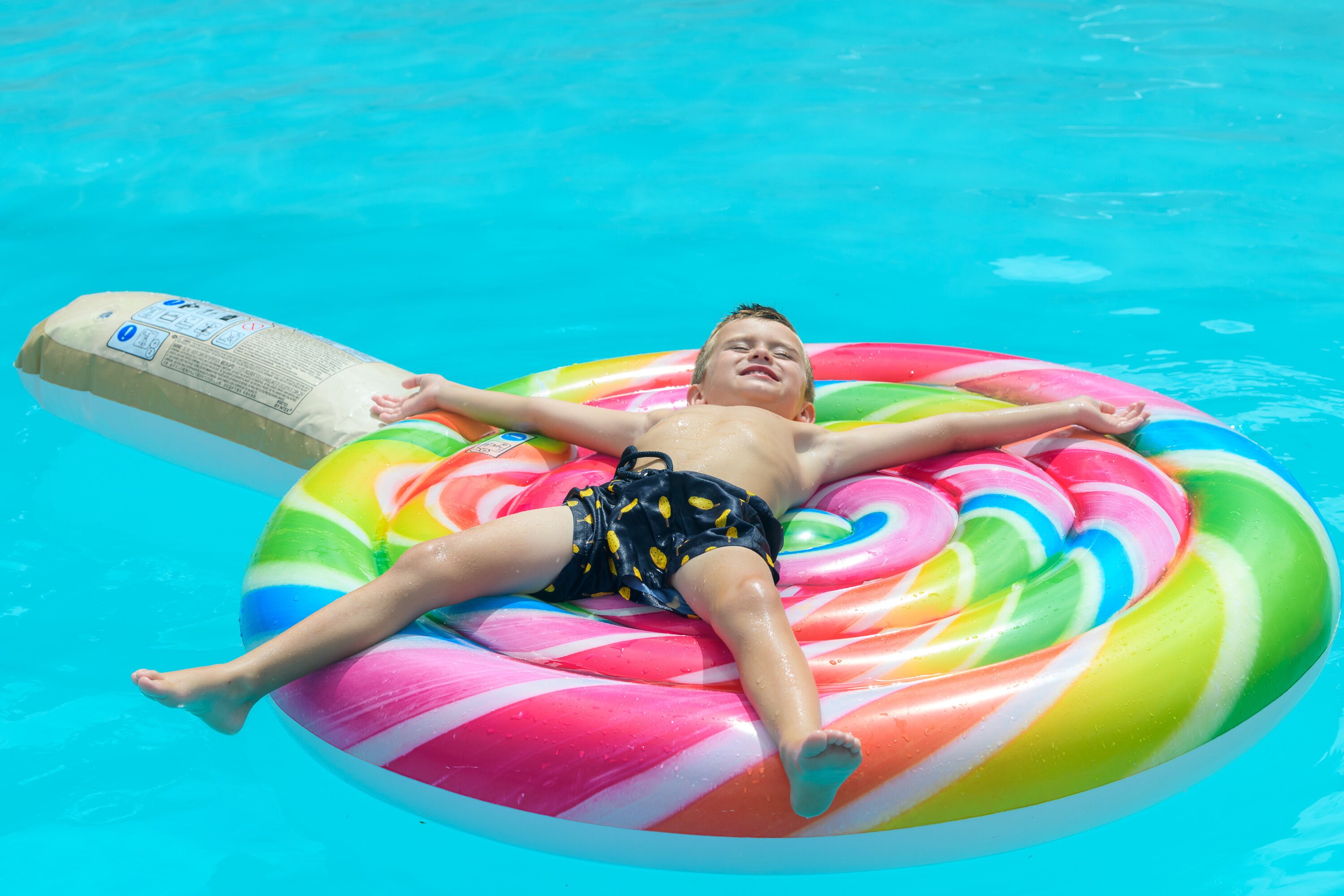Uma pessoa deitada em um círculo inflável colorido em uma piscina.