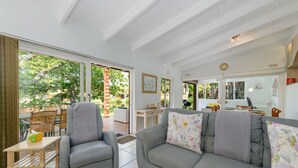 A spacious living room with a grey sofa, a grey armchair, and a wooden coffee table. There is a large window providing a view of the outdoors. - San Lameer Villa Rentals  2301 (Southbroom)