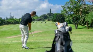 Un campo da golf con un golfista che si prepara a tirare, una borsa da golf e un cielo sereno.