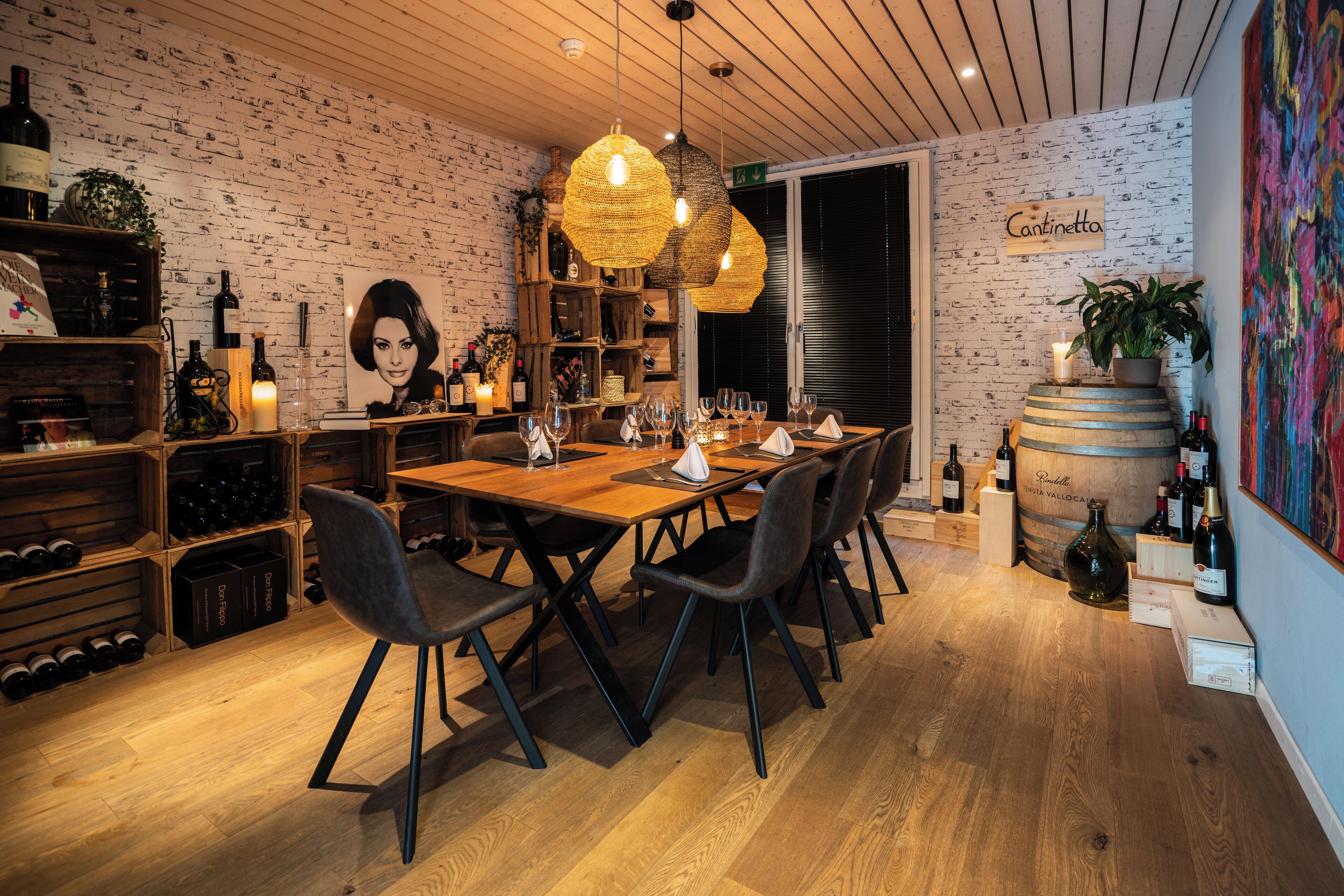 Un restaurante con pared de ladrillo, muebles de madera y lámparas colgantes.