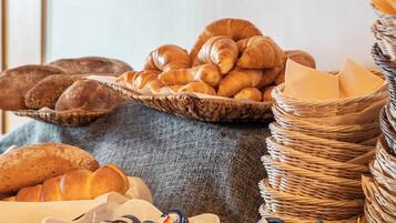 Une variété de viennoiseries et de pains, disposés sur une table avec un panier en osier et un tissu.