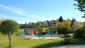 A pool area with a small building, a fenced deck, and lounge chairs. - Les Filolies (Saint-Andre-d'Allas)