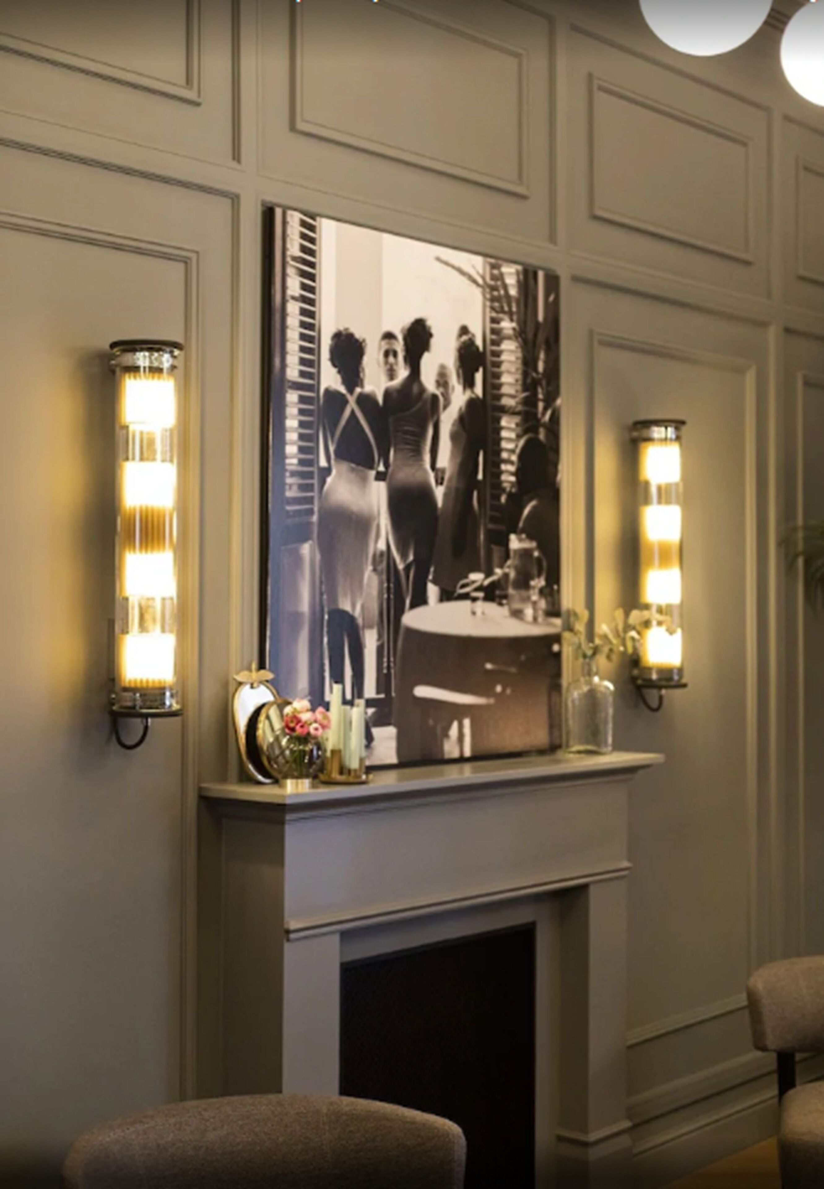 A fireplace with a framed black and white photograph above it, flanked by wall sconces.