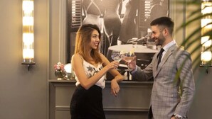 A man and a woman standing in a lobby with a fireplace, a couch, and a wall-mounted light fixture. - Maldà Singular Hotel (Barcelona)