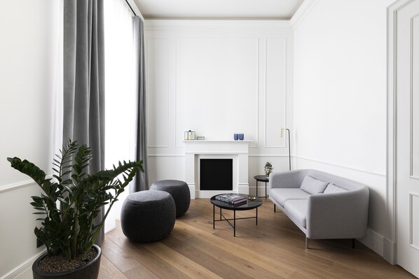 A modern living room with a grey sofa, a coffee table, and a potted plant. - Maldà Singular Hotel (Barcelona)