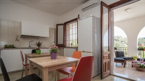 Une cuisine moderne avec une table en bois, des chaises rouges et noires, et un réfrigérateur. Il y a une fenêtre qui donne sur l’extérieur.