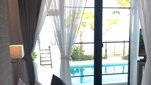 A hotel room with a bed, a view of a pool, and a balcony. - La Playa Beach Front Pool Villa Cha-am (Cha-am)