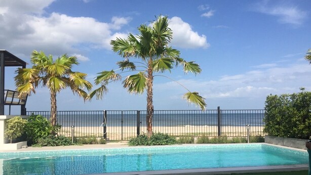 A swimming pool with a view of the beach and palm trees. - La Playa Beach Front Pool Villa Cha-am (Cha-am)