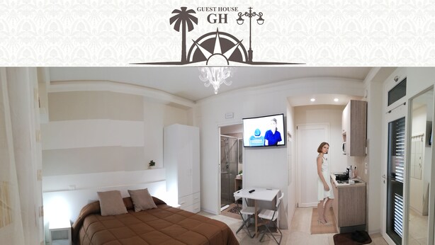 Una habitación de hotel moderna con cama, escritorio, televisor y kitchenette.