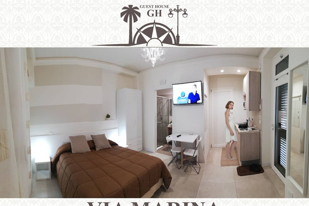 Una habitación de hotel moderna con cama, escritorio, televisor y kitchenette.