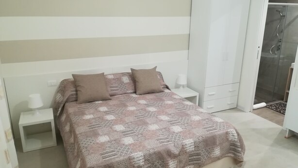 Ein Schlafzimmer mit einem Bett, zwei Nachttischen, einem Kleiderschrank und einer Dusche.