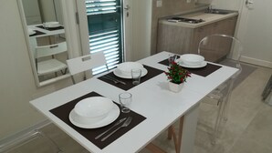 Una mesa de comedor con platos blancos, individuales negros y cristalería transparente.