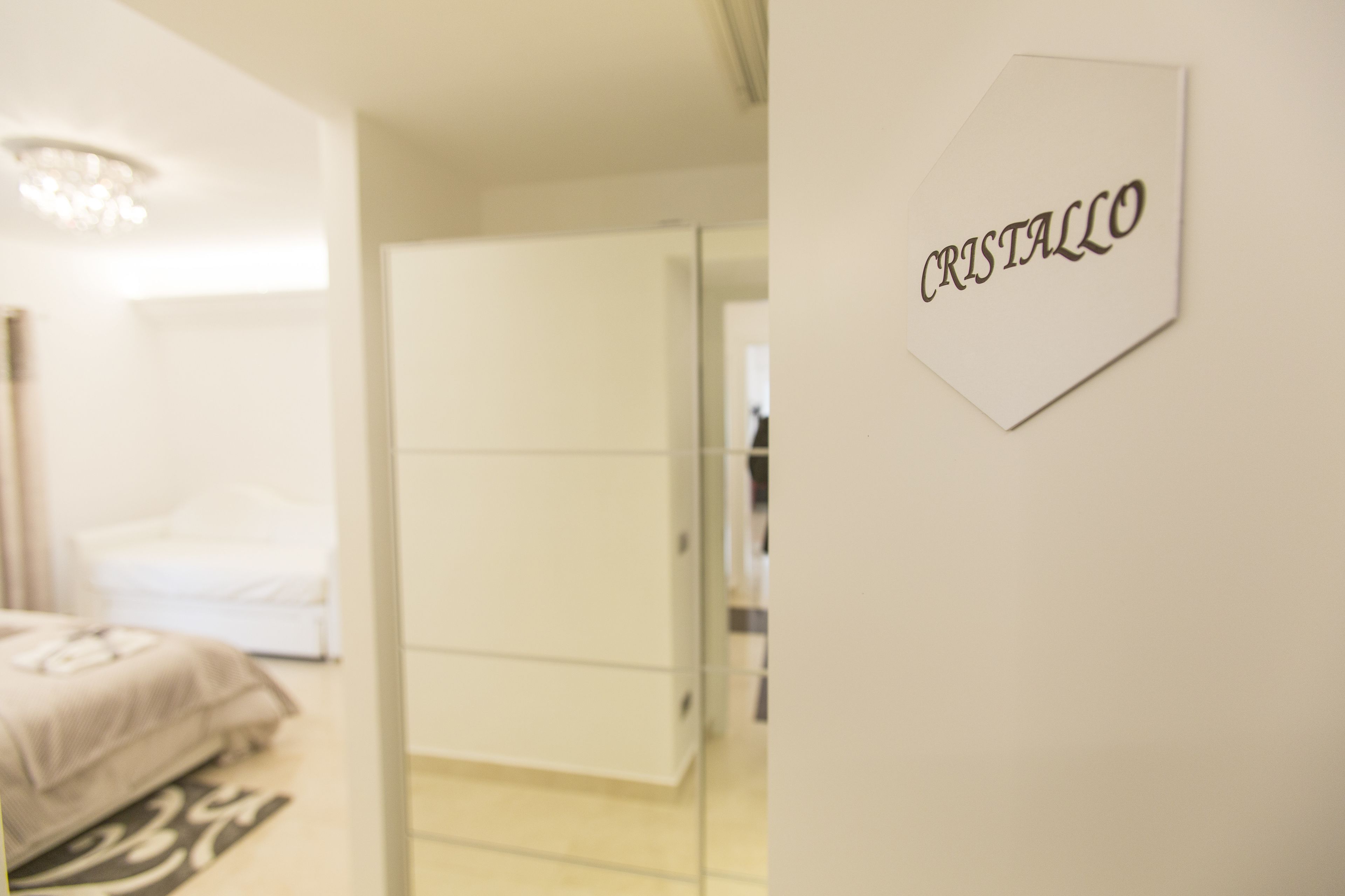Hotellihuoneessa on sänky, vaatekaappi ja seinälle kiinnitetty kyltti, jossa lukee ”CRISTALLO”.