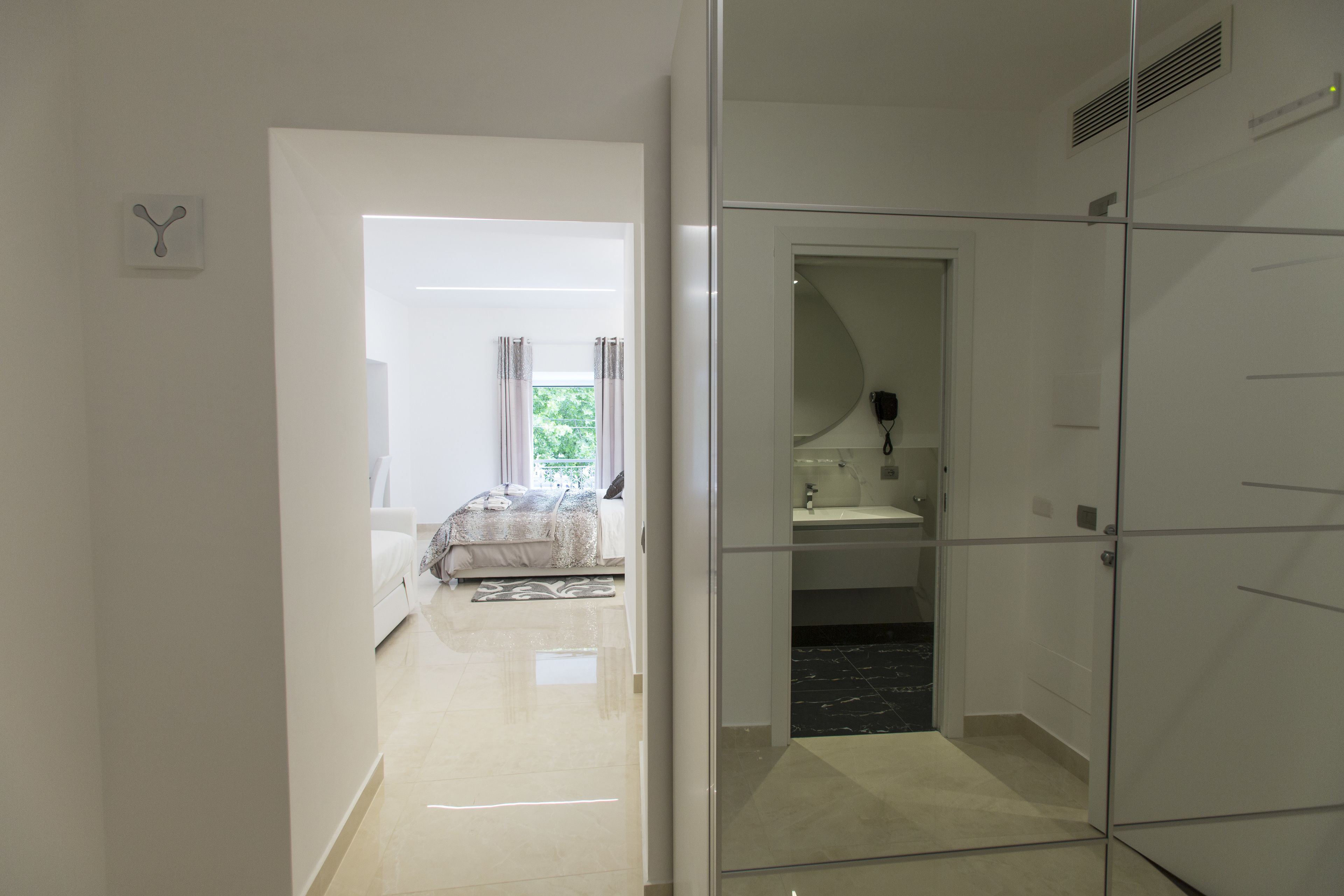 A modern bedroom with a bed, a bedside table, and a window with curtains.