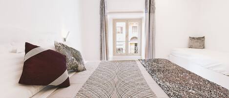 Une chambre d’hôtel moderne avec un grand lit, un tapis décoratif et une vue sur la ville par la fenêtre.