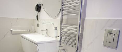 A modern bathroom with a white toilet, a bidet, a sink, and a mirror.