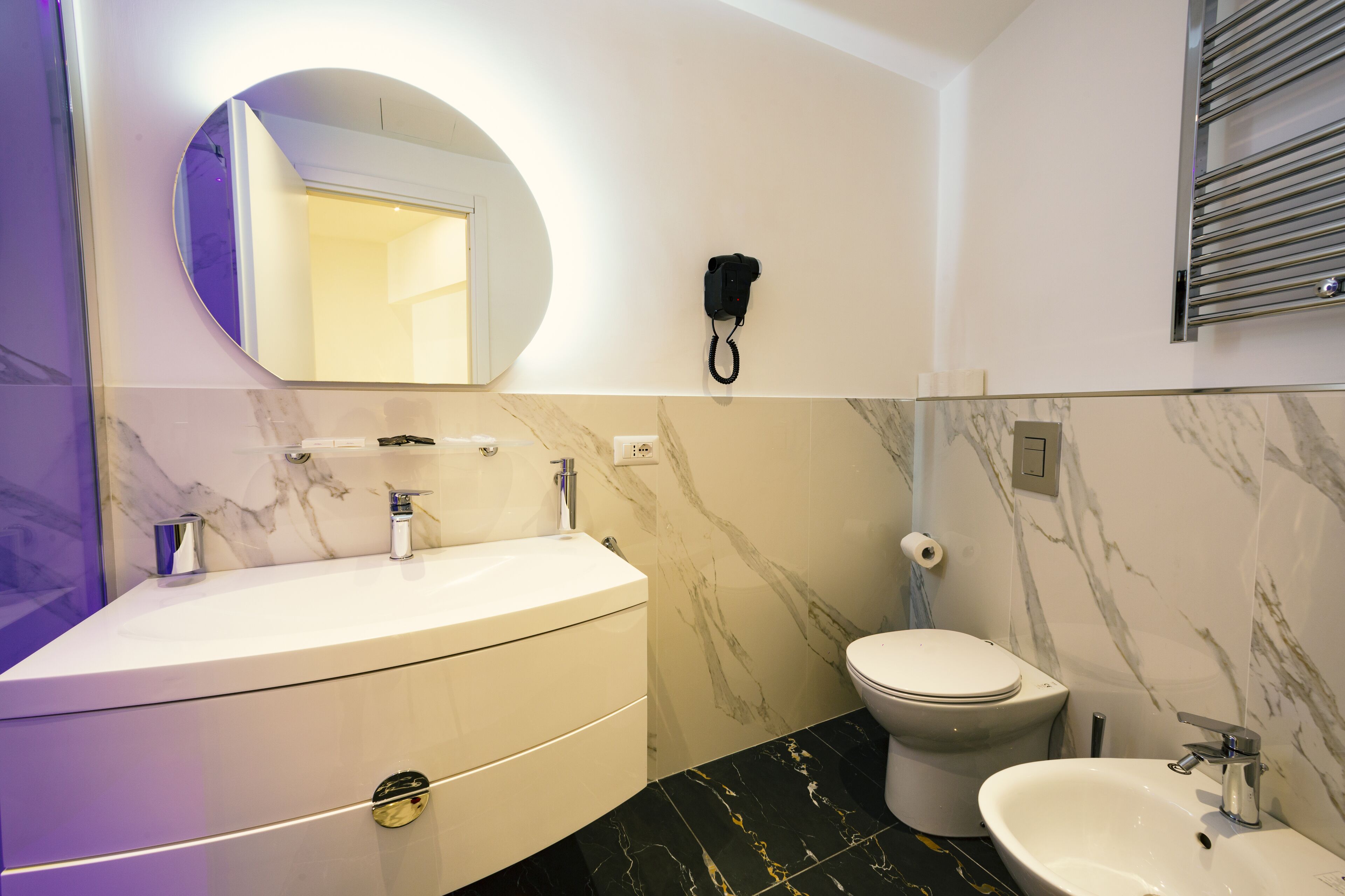 A modern bathroom with a marble vanity, a toilet, and a sink.