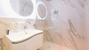 A modern bathroom with a marble vanity, a large mirror, and a glass-enclosed shower area. - San Pietro Grand Suite (Rome)