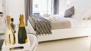 A modern hotel room with a bed, a bedside table with two bottles of champagne, and a view of the city through the window. - San Pietro Grand Suite (Rome)