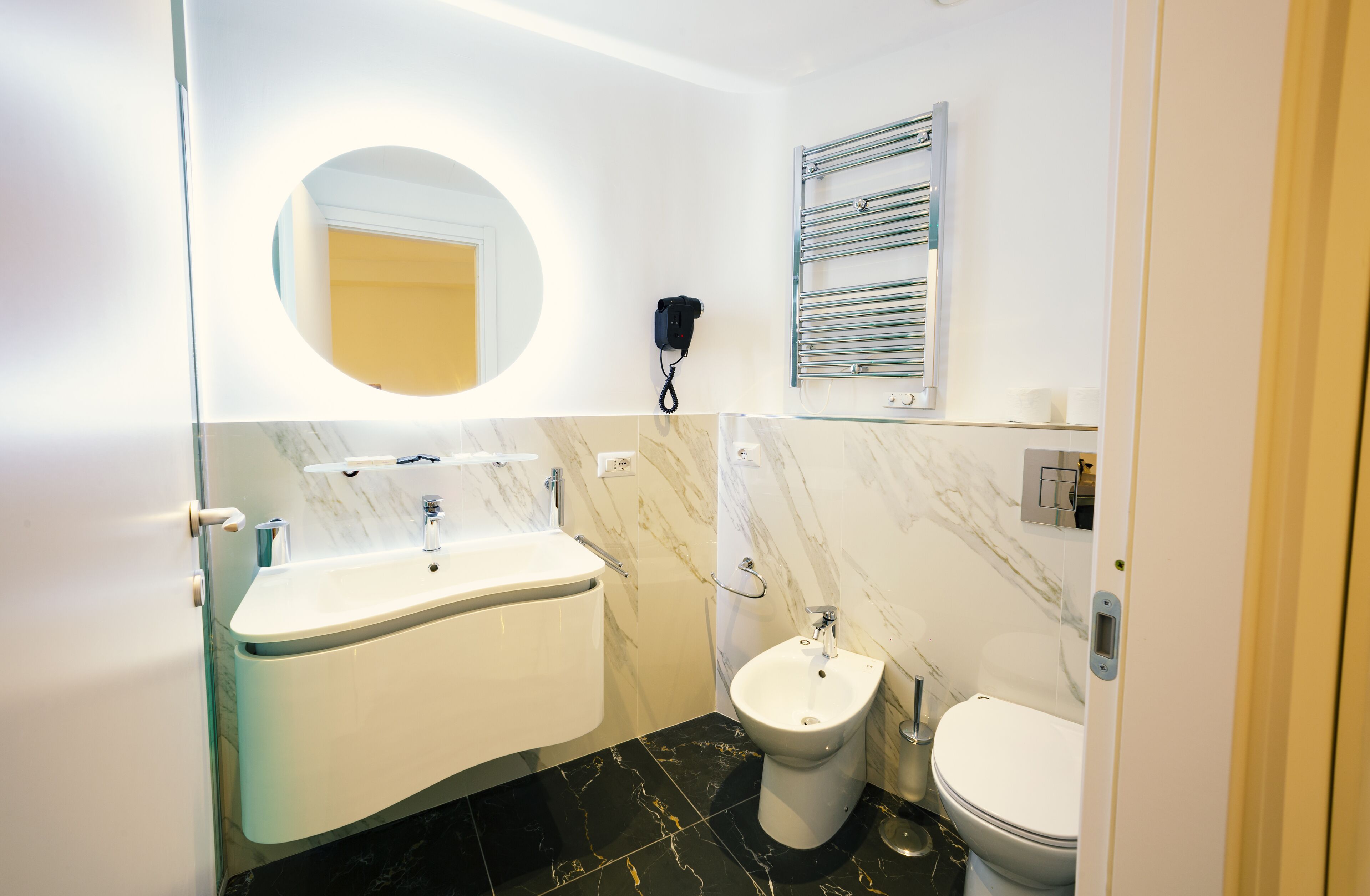 Un baño moderno con un lavamanos blanco, un bidé y un inodoro.