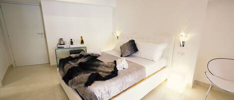 Une chambre à coucher moderne avec un grand lit, des tables de chevet et un fauteuil.