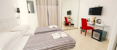 A hotel room with two beds, a TV, a desk with a chair, and a minibar.